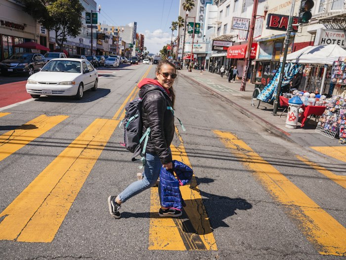 Woman walking across a sunny city street